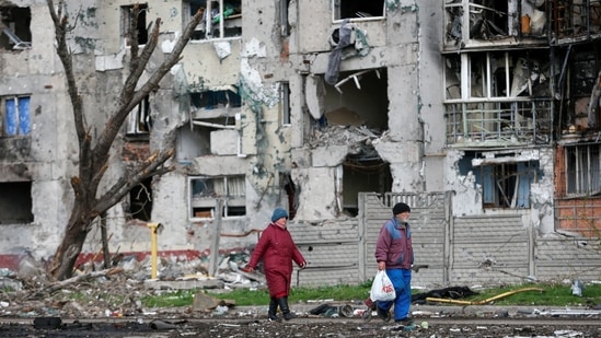 People walk near a residential building destroyed during Ukraine-Russia conflict in the southern port city of Mariupol.(Reuters photo)