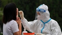 Um trabalhador médico coleta uma amostra de um residente durante o teste em massa para COVID-19 no distrito de Chaoyang, em Pequim. 