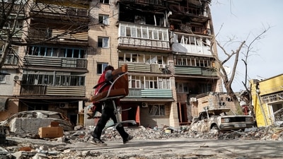 A local resident carries an armchair outside a block of flats heavily damaged during Ukraine-Russia conflict in the southern port city of Mariupol, Ukraine. (REUTERS)