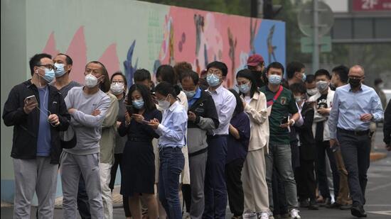 Residents and office workers wearing masks line up for mass Covid testing near the commercial office complex in Chaoyang district, Beijing, China on Monday. (AP) Residents and office workers wearing masks line up for mass Covid testing near the commercial office complex in Chaoyang district, Beijing, China on Monday. (AP)