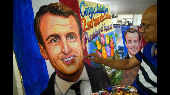 An artist gives final touches to a painting of French President and La Republique en Marche (LREM) party candidate for re-election Emmanuel Macron after his victory in France's presidential election, in Mumbai on April 25, 2022. (Photo by Punit PARANJPE / AFP) (AFP)