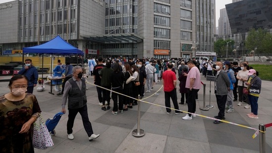 Beijing residents and office workers wearing face masks line up for mass coronavirus testing outside a commercial office complex at the central business district, Monday.(AP)