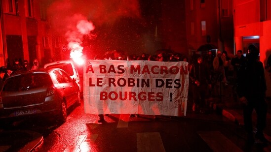 People attend a demonstration after the announcement of results of the 2022 French presidential election. Banner reads: "Down with Macron, Robin [Hood] of the bourgeoisie"&nbsp;