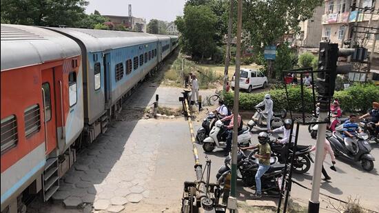 Commuters waiting at the Ishmeet Singh Chowk railway crossing after the train developed a snag. (HT Photo)