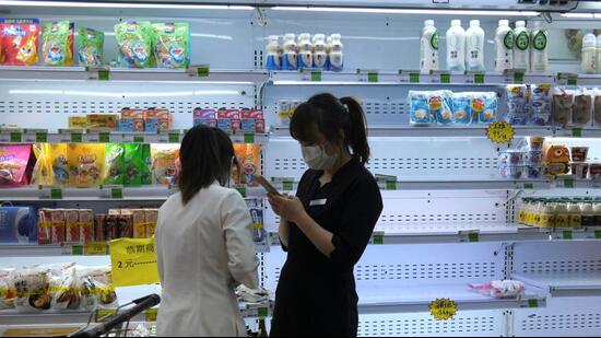 Customers shop in front of a half-empty freezer for diary products, following Covid-19 outbreak, at a supermarket in Beijing, China, on Monday. (REUTERS)