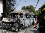 Police officers and members of the investigation team gather near a van after a blast at the entrance of the Confucius Institute University of Karachi.