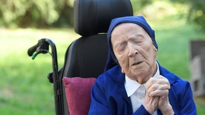 Sister Andre, Lucile Randon in the registry of birth, the eldest French and European citizen, prays in a wheelchair, on the eve of her 117th birthday. (AFP file)