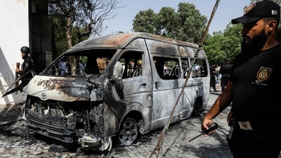Police officers and members of the investigation team gather near a van after a blast at the entrance of the Confucius Institute University of Karachi. (REUTERS)