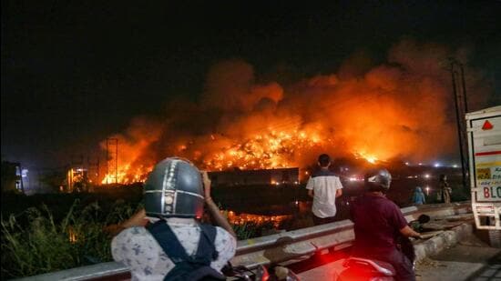मंगलवार रात उत्तरी दिल्ली के भलस्वा लैंडफिल साइट पर लगी भीषण आग को राहगीरों ने देखा (पीटीआई)