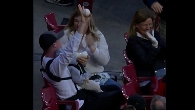 A screengrab of the video of a man catching a ball at a baseball game while feeding his kid.&nbsp; (@Reds/Twitter )