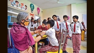 A healthcare worker administers a dose of the Covid-19 vaccine to a student in the age group of 12 to 14 years, at a school in Bikaner on Tuesday. (PTI) A healthcare worker administers a dose of the Covid-19 vaccine to a student in the age group of 12 to 14 years, at a school in Bikaner on Tuesday. (PTI)