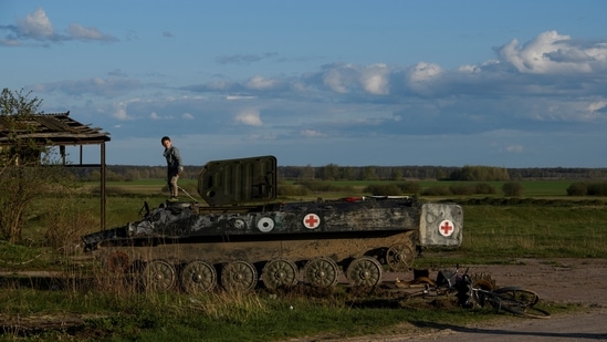 Local boy Faddei stands atop a destroyed Russian armoured military vehicle in the village of Kolychivka, in Chernihiv region.