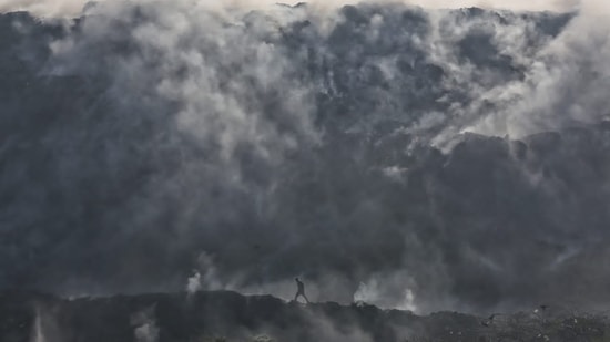 Firefighting teams poured truckloads of sand and mud to douse the Bhalswa landfill fire.(HT Photo/Sanchit Khanna)