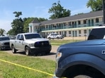 Law enforcement inspect the Biloxi Broadway Inn Express, cordoned off by crime scene tape and vehicles. The fatal shooting at the hotel on Mississippi’s Gulf Coast has police in a standoff with the suspect at a business a few miles away.