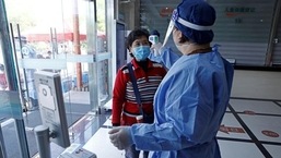 Um trabalhador em traje de proteção mede a temperatura corporal de uma mulher durante uma sessão de vacinação contra Covid-19 para idosos, em um centro de serviço comunitário de saúde no distrito de Fengxian, em Xangai, China.  (REUTERS)
