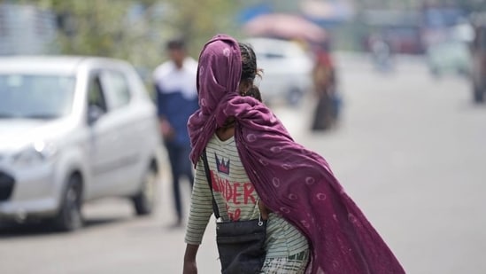 A girl covers her face with a scarf to protect herself from the sun on a hot summer afternoon in the outskirts of Jammu, India, Thursday, April 28, 2022. (AP Photo/Channi Anand) (AP)