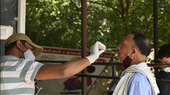 A health worker collects swab samples of a woman for Covid-19 testing, in Gurugram on Thursday. (Vipin Kumar/HT PHOTO)