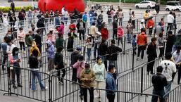 Pessoas fazem fila em um local improvisado de teste de ácido nucleico em meio ao surto de Covid-19, no distrito de Chaoyang, em Pequim, na China, na sexta-feira.  (REUTERS)