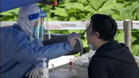 A worker wearing a protective suit swabs a man's throat for a Covid-19 test at a testing site in an office complex in Beijing on Friday.  (AP)