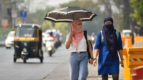 Women seen using scarves and umbrellas to protect themselves from the heat. (HT PHOTO)