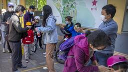 People wearing masks check their smartphones to show proof of a negative Covid-19 test within the past 48 hours as they enter a public park in Beijing, on Saturday, the first day of the Labour Day holiday period in China. (AP)