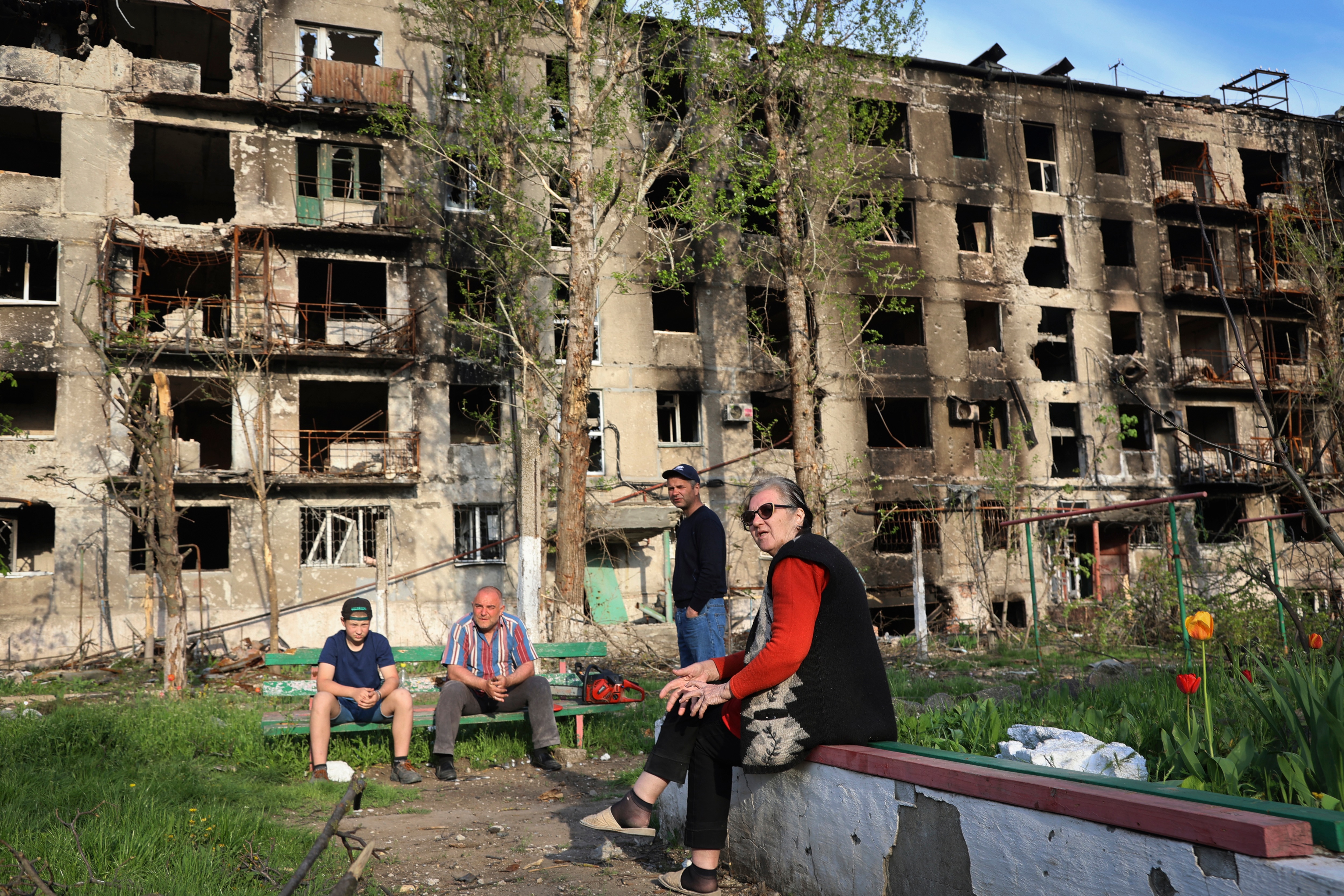 Local residents sit in the yard of their damaged building in Mariupol.&nbsp; (AP)