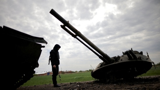 A Ukrainian service member inspects a destroyed Russian Armoured Personnel Carrier (APC), amid Russia's invasion of Ukraine, in the Zaporizhzhia region, Ukraine.