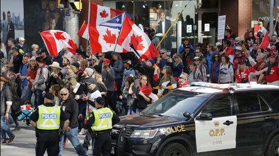 People march past police at a demonstration, part of a convoy-style protest participants are calling "Rolling Thunder," in Ottawa, Ontario, on Saturday, April 30, 2022. (Patrick Doyle/The Canadian Press via AP) (AP)