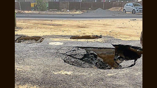 A pedestrian spotted craters forming on a newly laid service lane, and raised the alarm. Municipal corporation (MC) and National Highway Authority of India (NHAI) officials arrived at the spot, and a barricade was installed to divert traffic. (HT PHOTO )