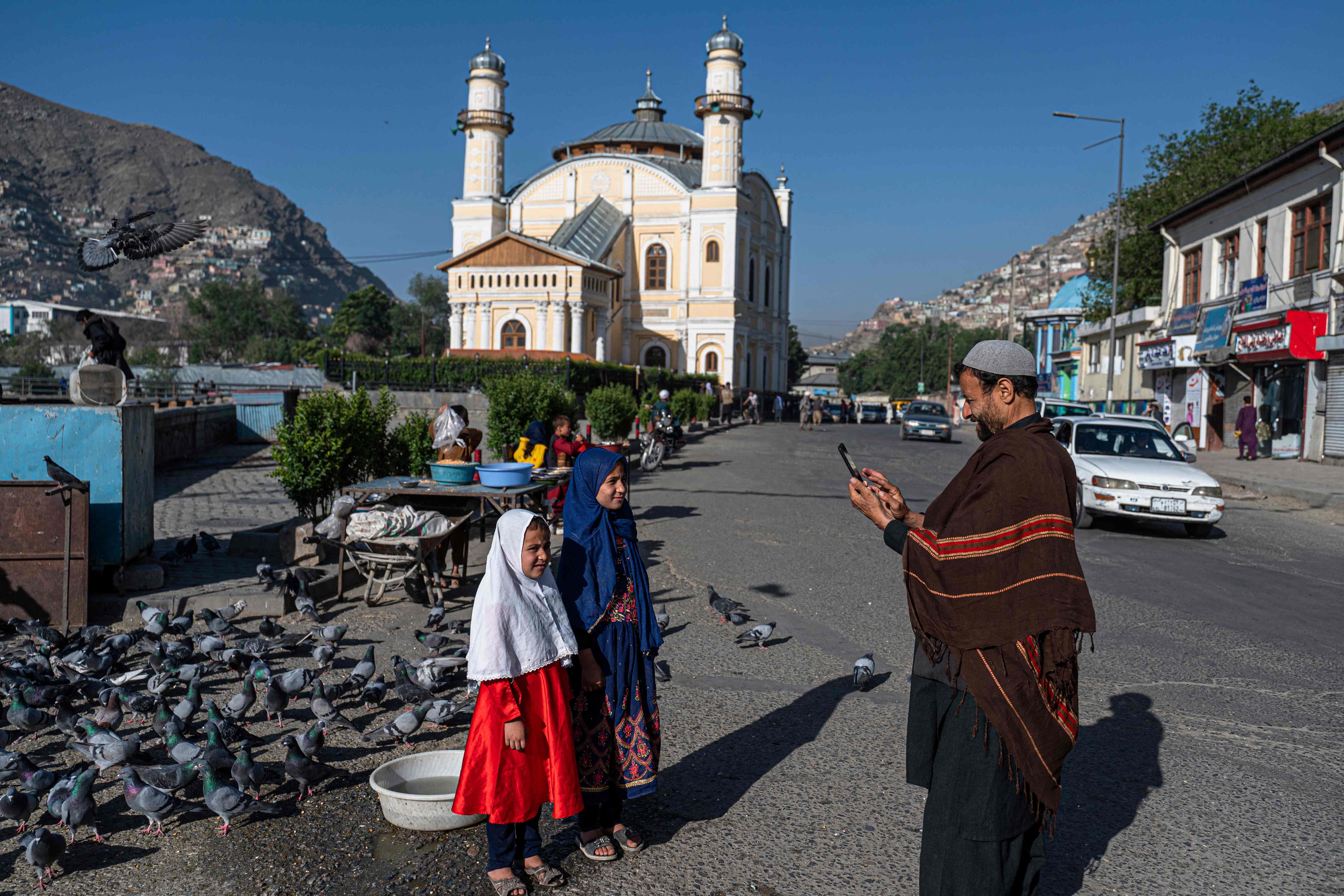 A Muslim devotee takes pictures with his mobile phone before offering Eid al-Fitr prayers, which marks the end of the holy fasting month of Ramadan outside a mosque in a street in Kabul on May 1, 2022.&nbsp; (Photo by Wakil KOHSAR / AFP)