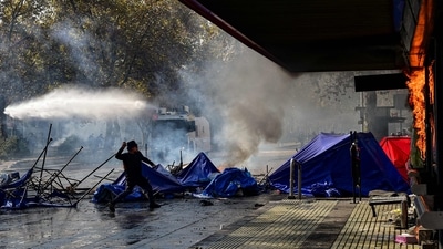 A demonstrator throws a stone at a business set on fire during clashes with riot police following a May Day march in Santiago. (AFP) A demonstrator throws a stone at a business set on fire during clashes with riot police following a May Day march in Santiago. (AFP)