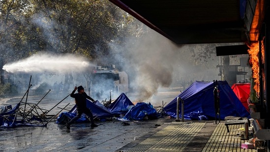 A demonstrator throws a stone at a business set on fire during clashes with riot police following a May Day march in Santiago.(AFP)