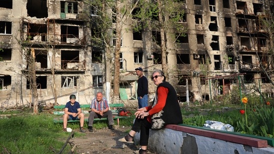 Local residents sit in the yard of their damaged building in Mariupol.&nbsp;(AP)