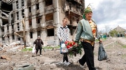 Mulheres passam por um prédio de apartamentos destruído em Mariupol, em território sob o governo da República Popular de Donetsk.