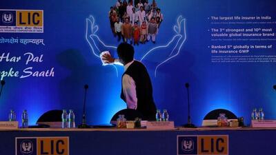 A man cleans a hoarding of Life Insurance Corporation of India (LIC) before the start of a news conference about the LIC initial public offering (IPO) launch, in Kolkata, (REUTERS File Photo)
