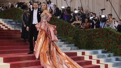 Blake Lively smiled for the cameras in a grand Atelier Versace gown, with husband Ryan Reynolds in brown velvet. (REUTERS)