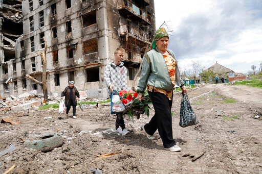 Women walk past a destroyed apartment building in Mariupol, in territory under the government of the Donetsk People's Republic. (AP) Women walk past a destroyed apartment building in Mariupol, in territory under the government of the Donetsk People's Republic. (AP)