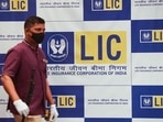 A man walks past a hoarding of Life Insurance Corporation of India (LIC) in Mumbai.