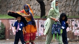 Women with kids walk amid a short spell of rain in Delhi on Wednesday.&nbsp;