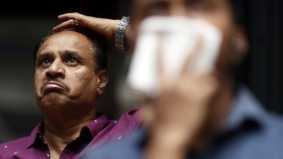 A man reacts as he looks at a screen displaying the Sensex results on the facade of the Bombay Stock Exchange (BSE) building in Mumbai. (REUTERS)