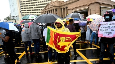 A demonstrator holds Sri Lanka's national flag as he takes part in a protest against the economic crisis in Colombo. (AFP) A demonstrator holds Sri Lanka's national flag as he takes part in a protest against the economic crisis in Colombo. (AFP)