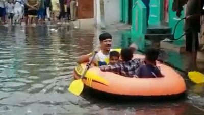 A video grab of locals using a boat in an inundated stretch of Hyderabad. (ANI Twitter)