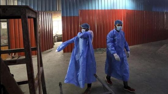 Workers put on personal protective suits before carrying the body of a Covid-19 victim for cremation in Delhi in September 2020 (AP File Photo)