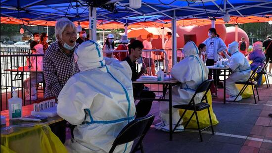 A health worker takes a swab sample from an elderly woman to be tested for Covid-19 at a makeshift testing site outside a museum along a street in Beijing, China on Wednesday. (AFP)