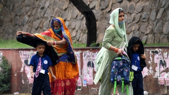Women with kids walk amid a short spell of rain in Delhi on Wednesday.&nbsp;(ANI)