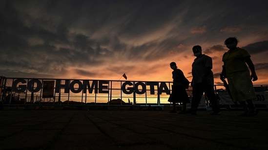 Protesters walk past a sign reading 'Go Home Gota' during an ongoing anti-government demonstration near the president's office in Colombo.(AFP)