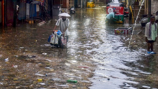 People wade through a flooded street following heavy rain, at Old Malakpet area in Hyderabad.(PTI)
