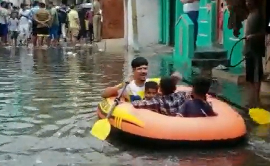 A video grab of locals using a boat in an inundated stretch of Hyderabad. (ANI Twitter)