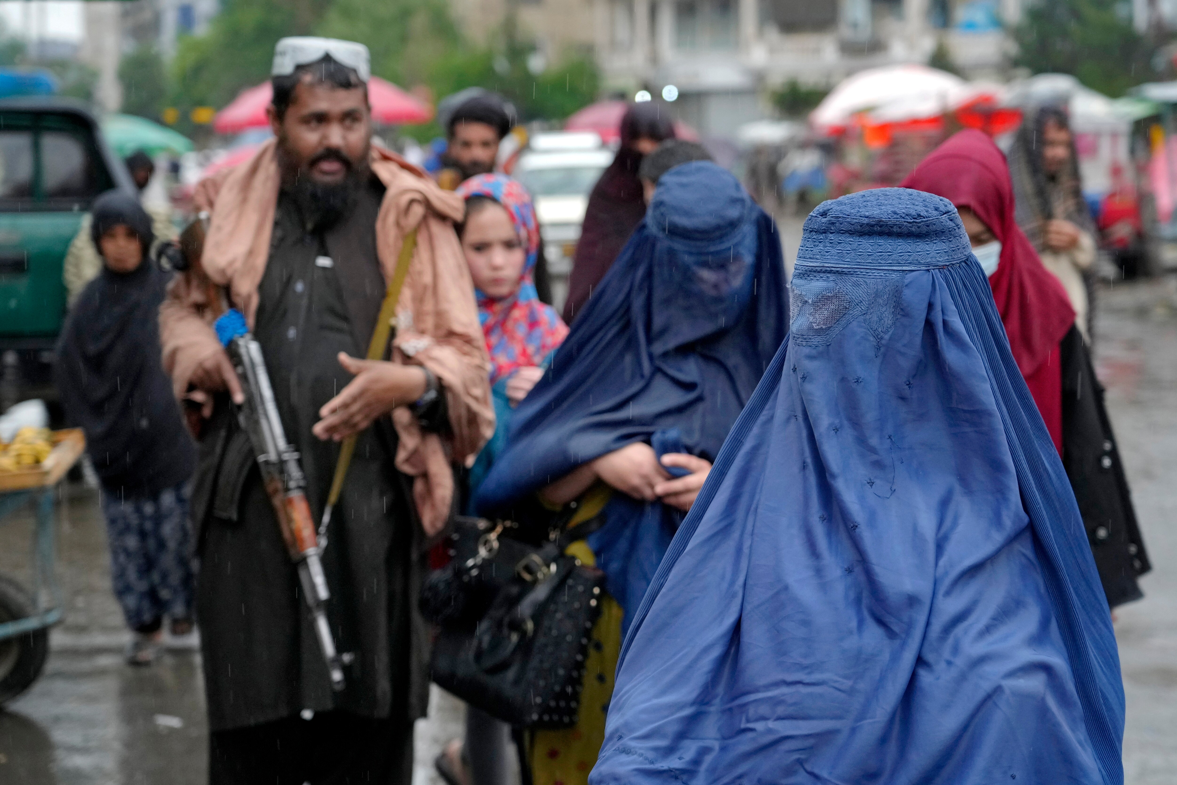 Women walk through the old market as a Taliban fighter stands guard, in the city of Kabul, Afghanistan. (AP file photo)