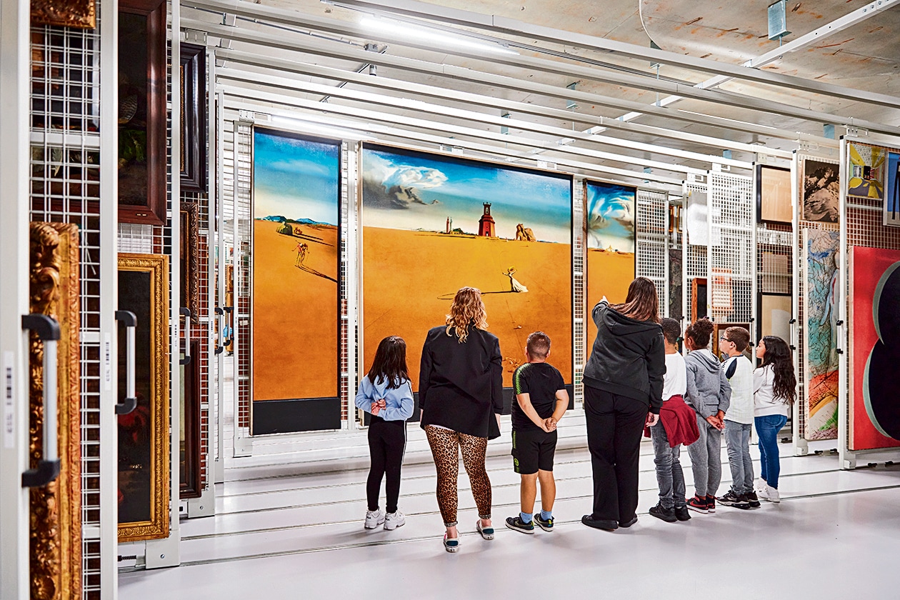 Visitors at the depot museum. The works are mounted on movable frames, just as they would be in storage. Because the art works are organised by size and climate zone (rather than genre, era or artist), visitors must necessarily browse, discover new names, make new connections. (Aad Hoogendoorn) Visitors at the depot museum. The works are mounted on movable frames, just as they would be in storage. Because the art works are organised by size and climate zone (rather than genre, era or artist), visitors must necessarily browse, discover new names, make new connections. (Aad Hoogendoorn)